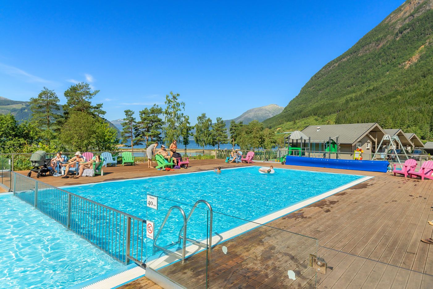 Oppvarma utandørsbasseng på Mikkelparken Ferietun, med spektakulær utsikt over Hardangerfjorden og grøne fjellsider.