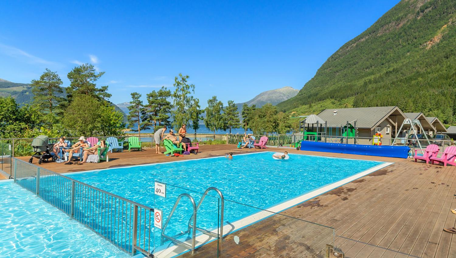 Oppvarma utandørsbasseng på Mikkelparken Ferietun, med spektakulær utsikt over Hardangerfjorden og grøne fjellsider.