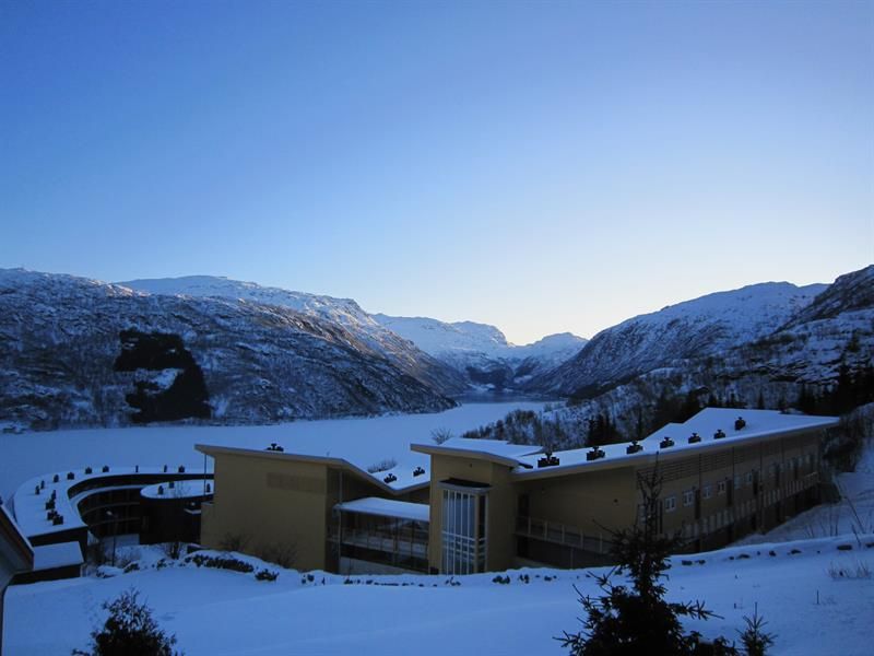 Vinterutsikt over Hordatun Hotel og Røldalsvatnet, omgitt av mektige fjell og eit snødekka landskap.