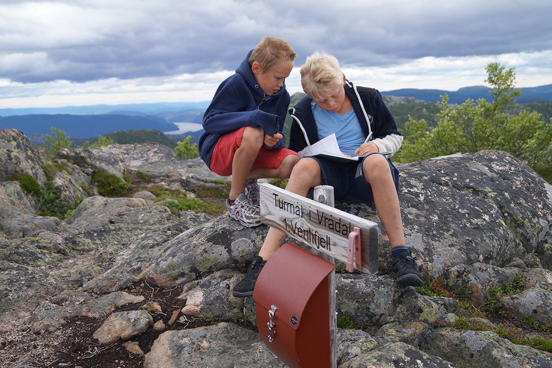 2 gutter ser på et kart på fottur til Venelifjell i Vrådal