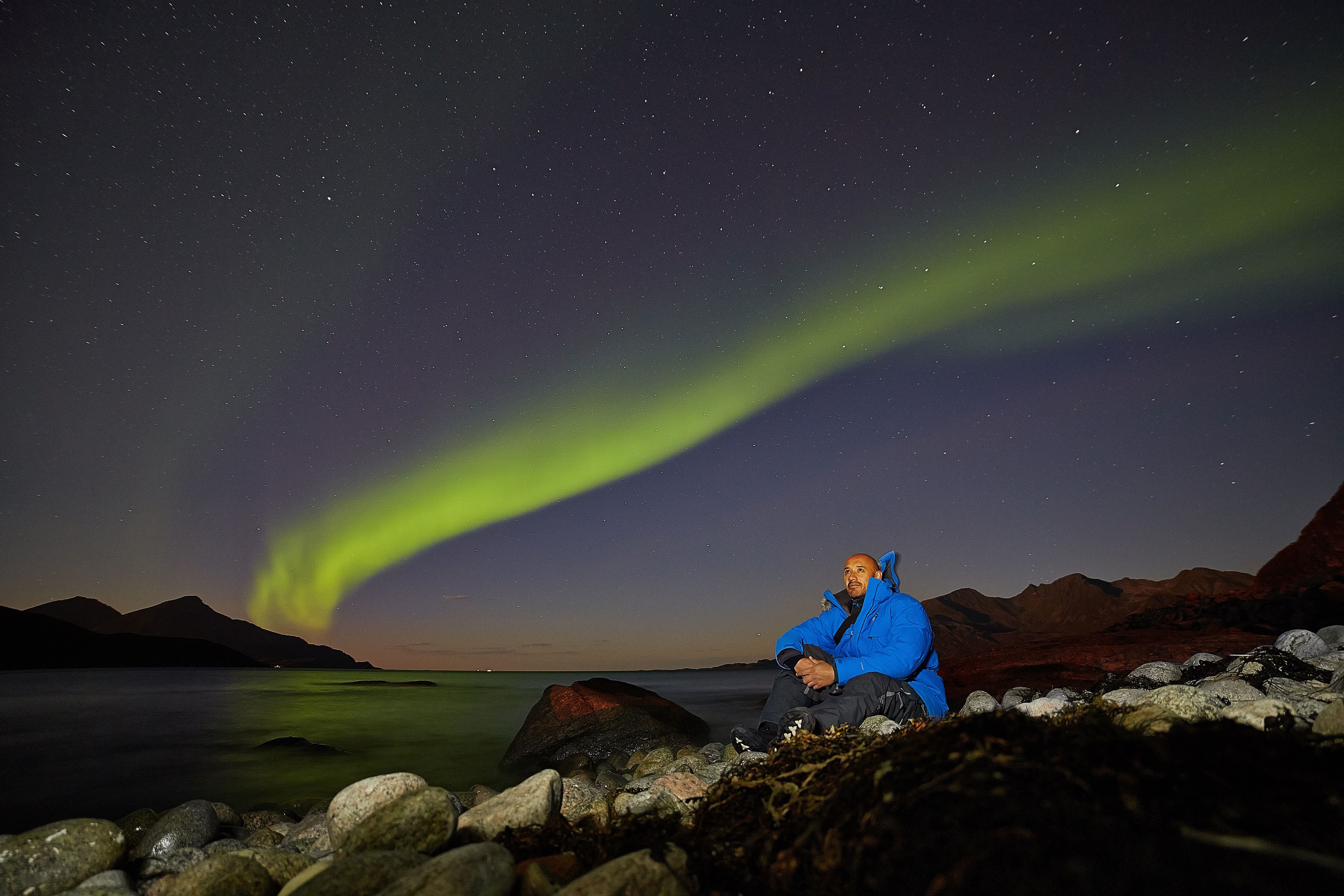 francisco som sitter i fjæra med nordlyset i bakgrunnen