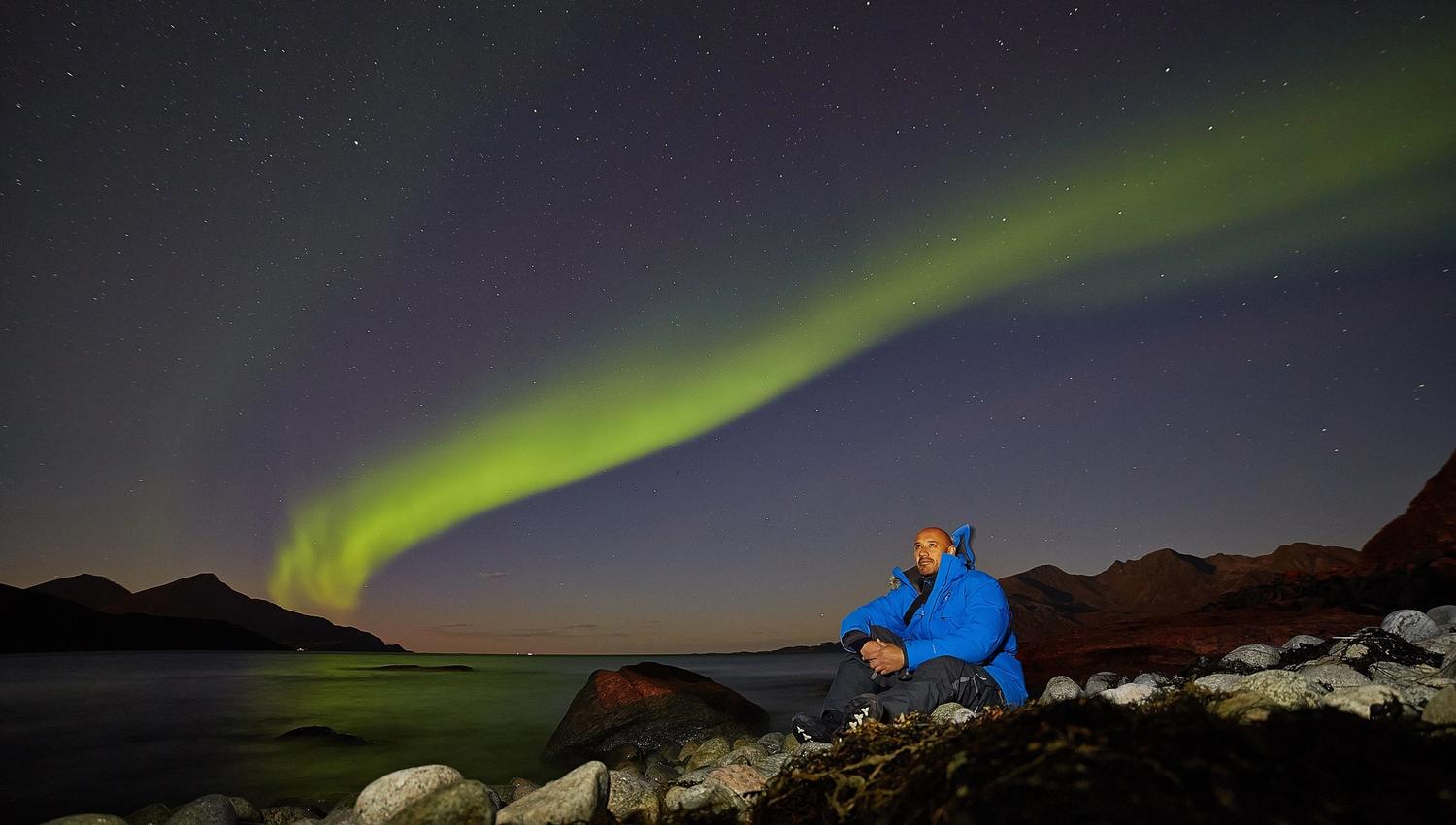 francisco som sitter i fjæra med nordlyset i bakgrunnen
