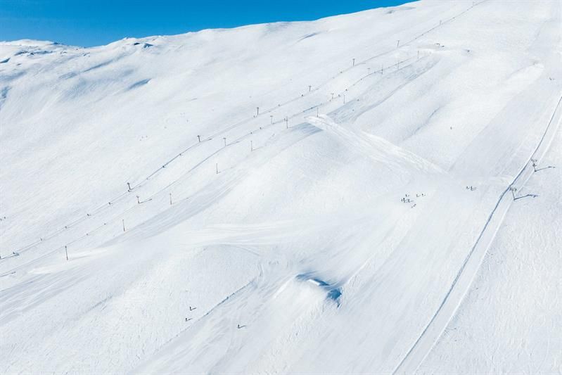 Sunny slopes and ski lifts at Røldal Ski Resort surrounded by snow-covered peaks.