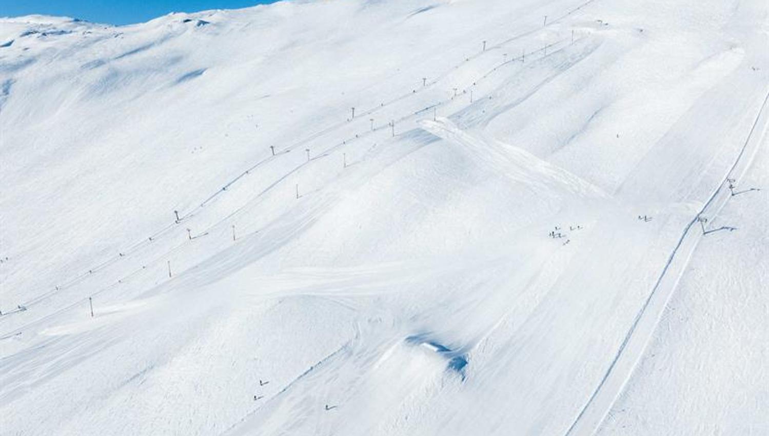 Sunny slopes and ski lifts at Røldal Ski Resort surrounded by snow-covered peaks.