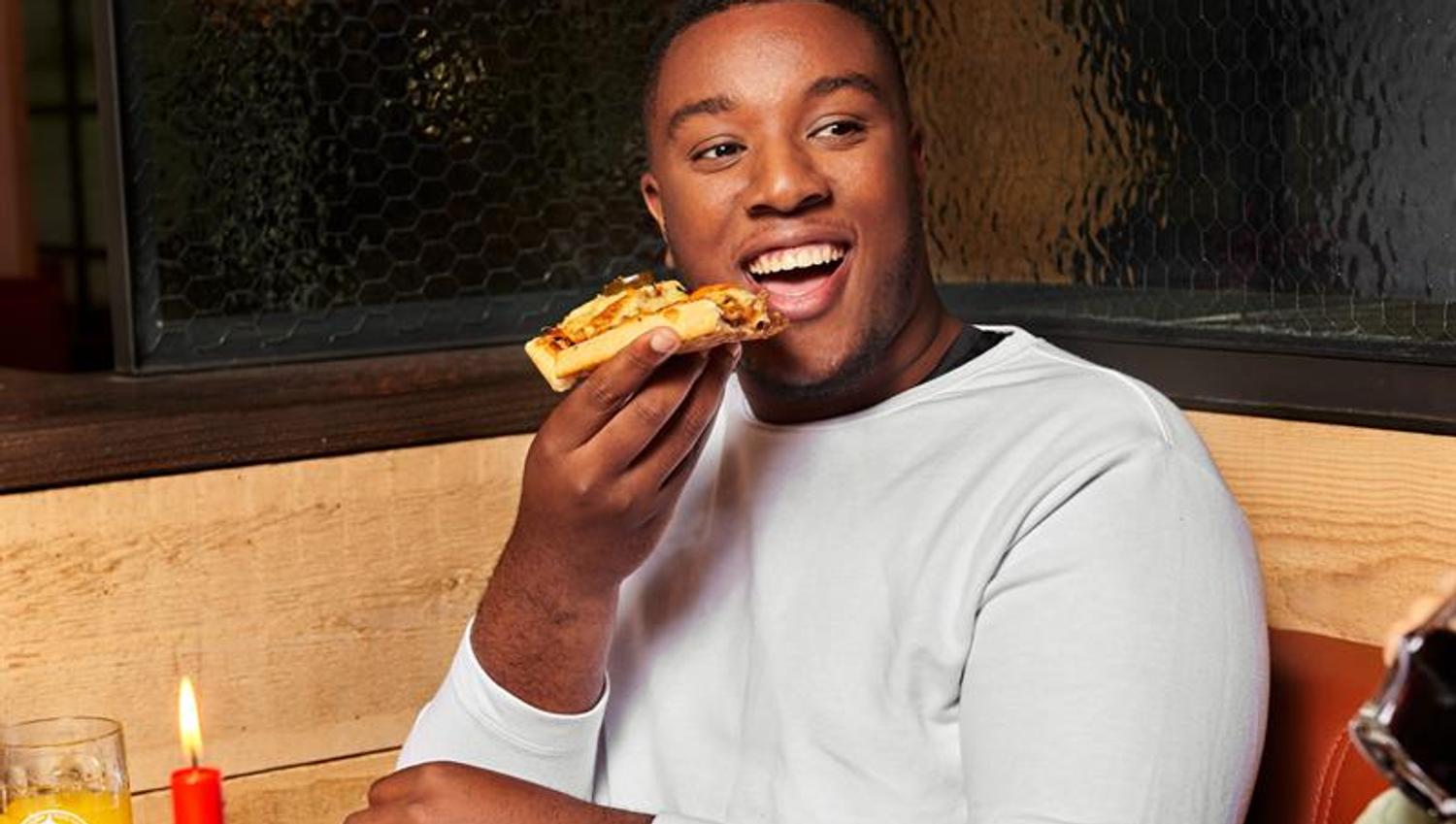 A guy eating a slice of pizza.