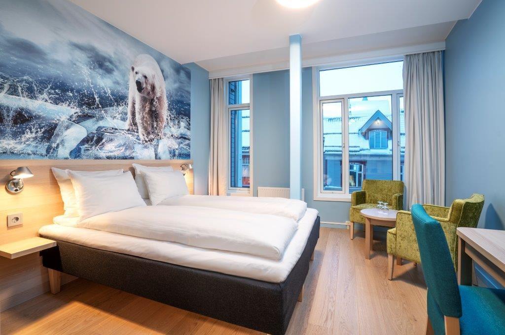 Moderne rom med stor seng, isbjørnmotiv på veggen og sittegruppe.