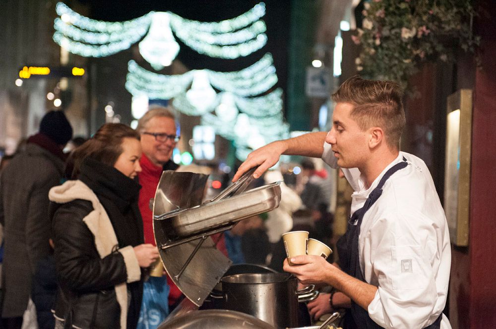 Personer som blir servert varm drikke av mann i hvit kokkejakke