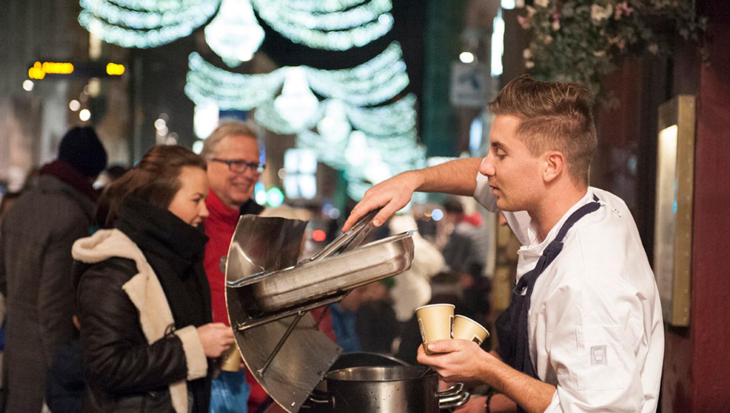 Personer som blir servert varm drikke av mann i hvit kokkejakke