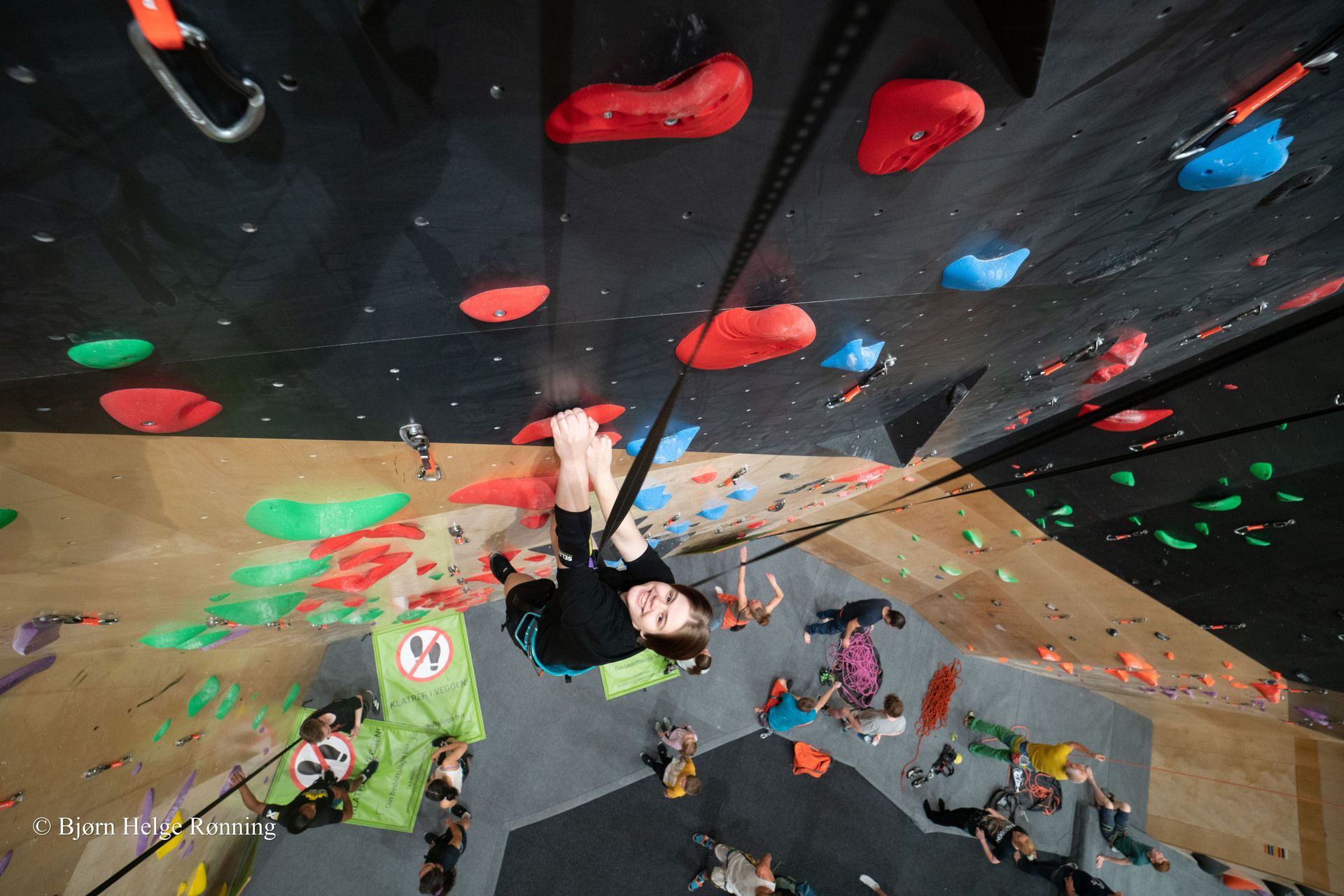 Noen som klatrer opp en bratt vegg i en innendørs klatrevegg