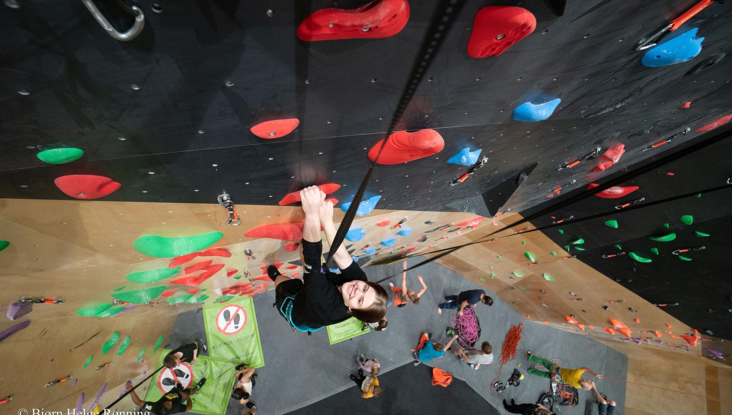 Noen som klatrer opp en bratt vegg i en innendørs klatrevegg