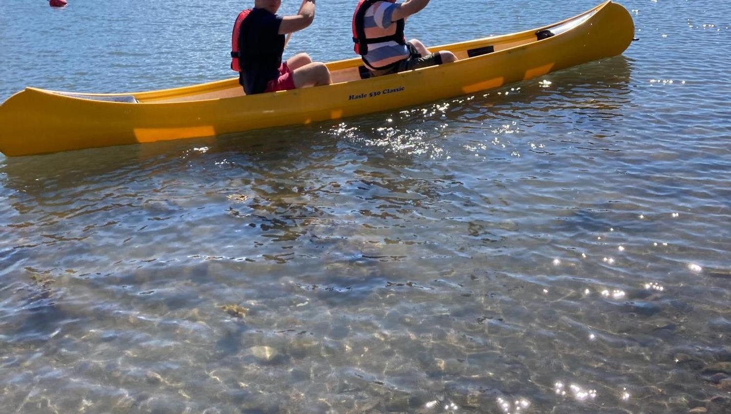 Two paddle in a yellow canoe