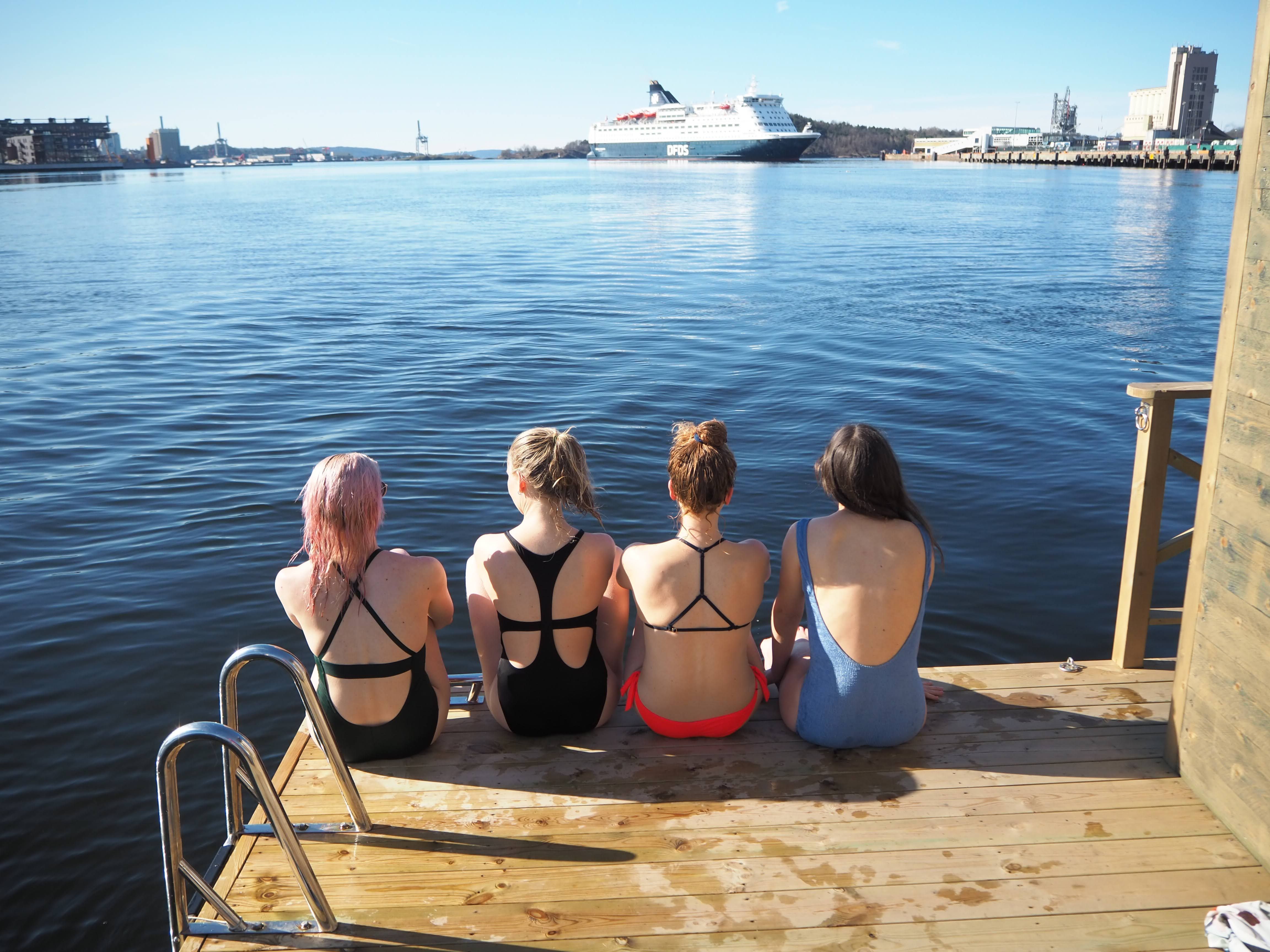 Fire jenter som sitter ved badstuen.