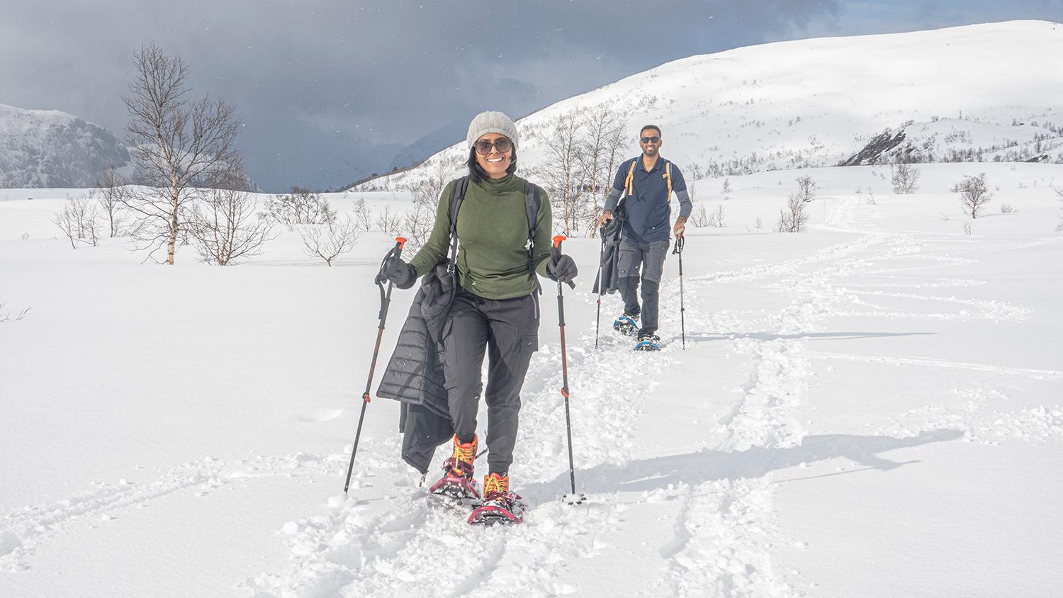 Two happy hikers snowshoeing through deep snow in the winter mountains of Hardanger.