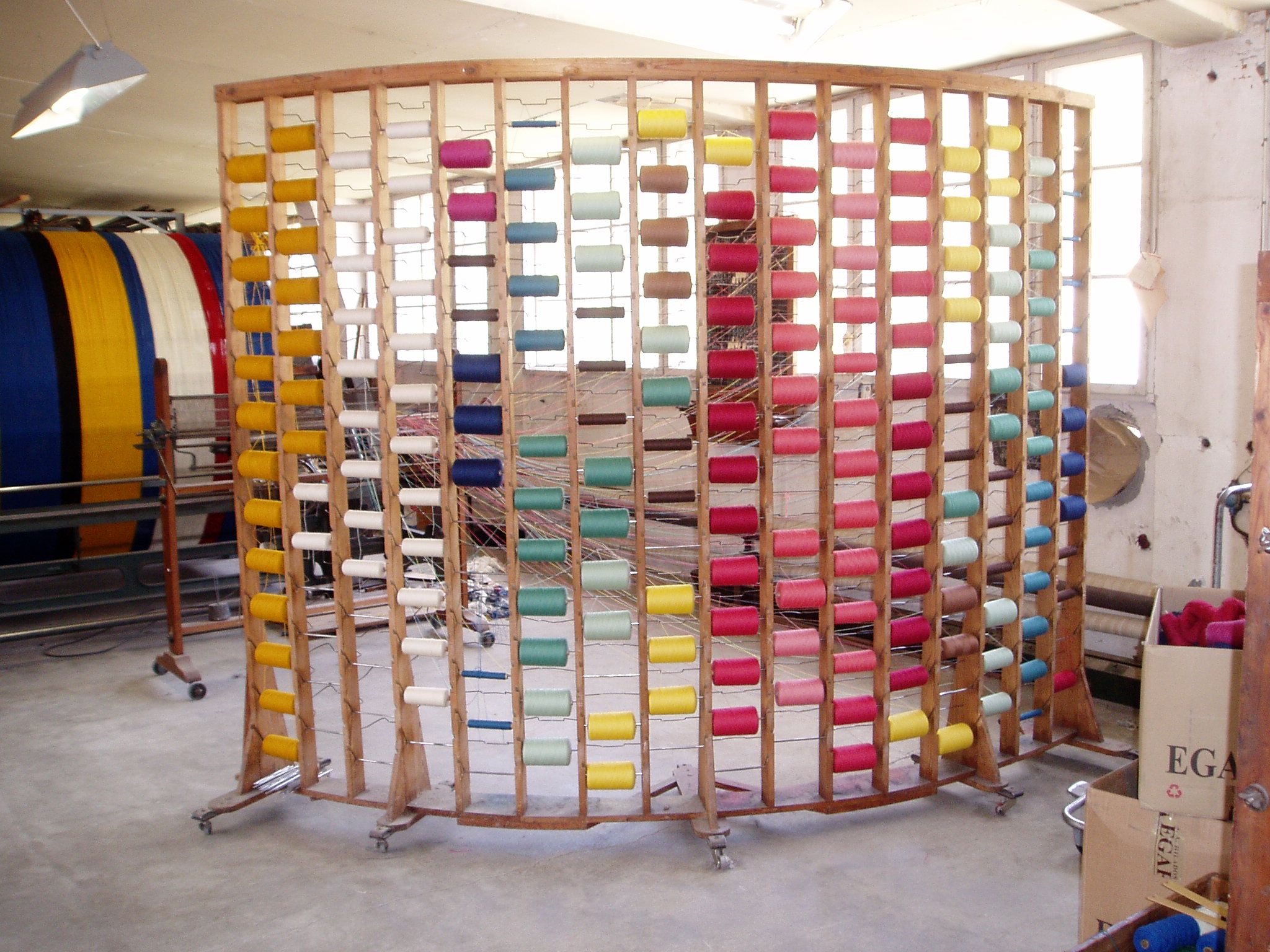 Different colors and shades of yarn neatly arranged on a shelf.
