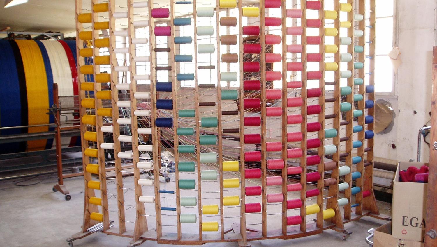 Different colors and shades of yarn neatly arranged on a shelf.