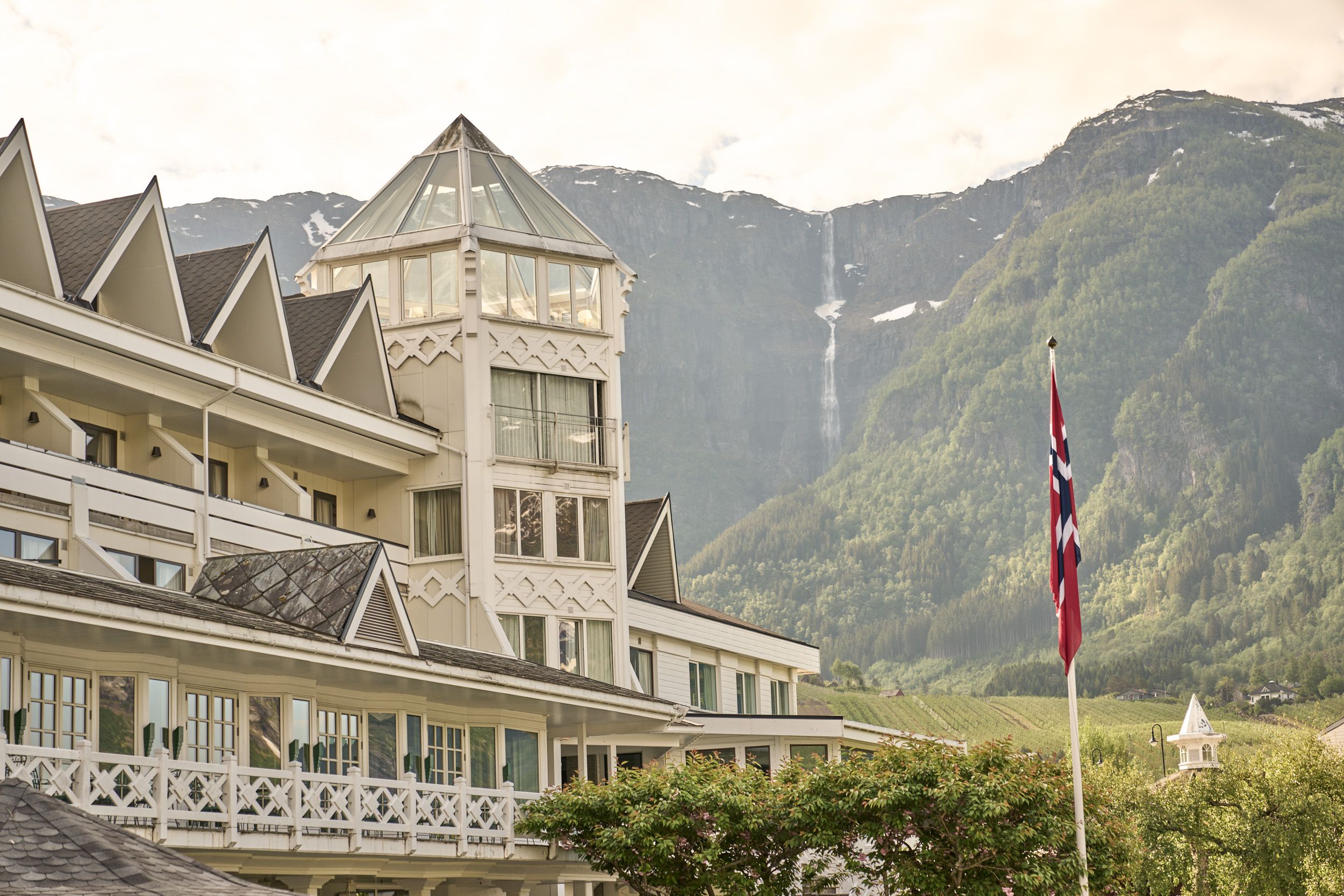 Det ikoniske tårnet på Hotel Ullensvang med fossefall i fjellsida som bakteppe.