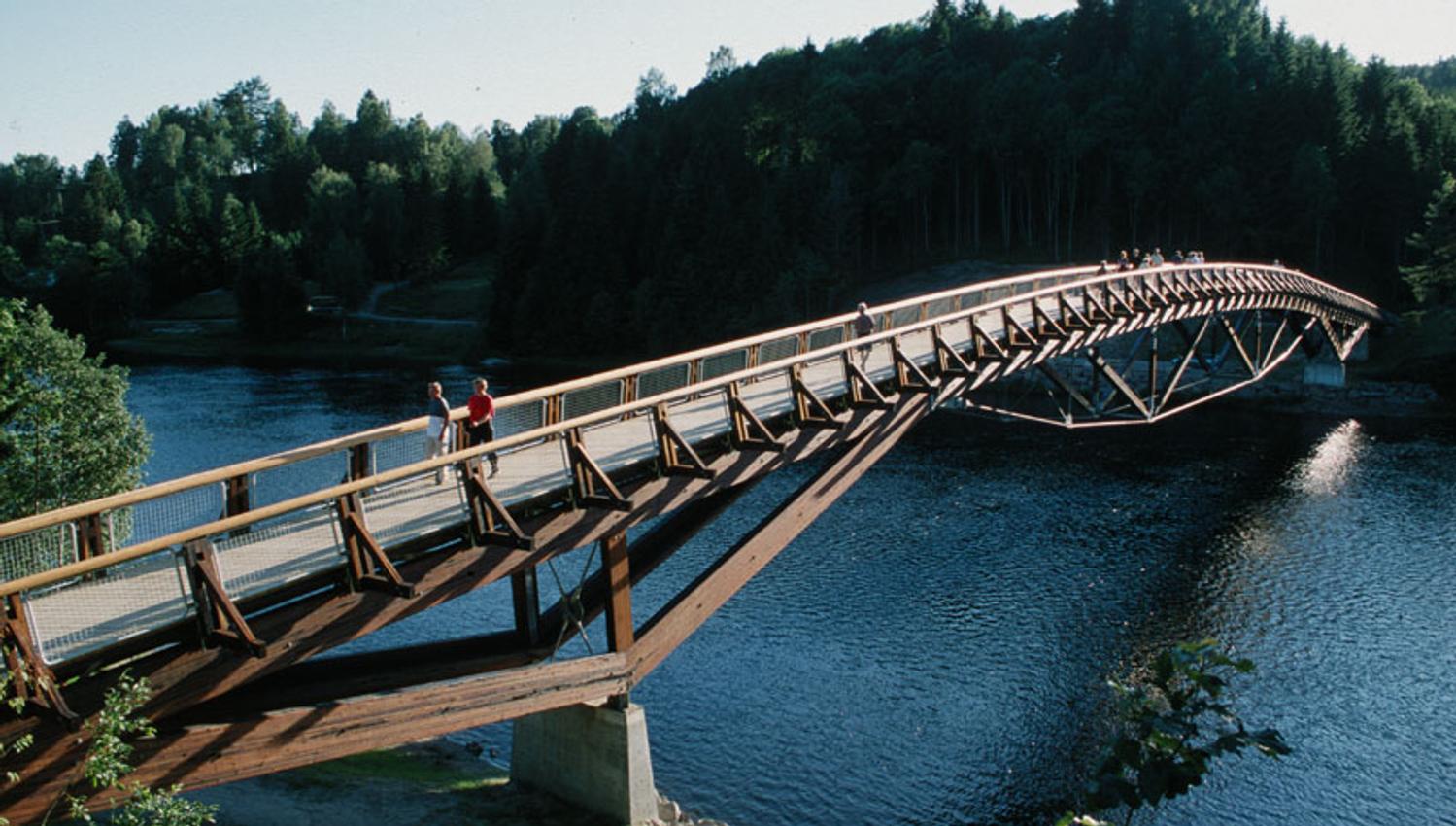 Flere personer går over en bro med Numedalslågen som renner under.