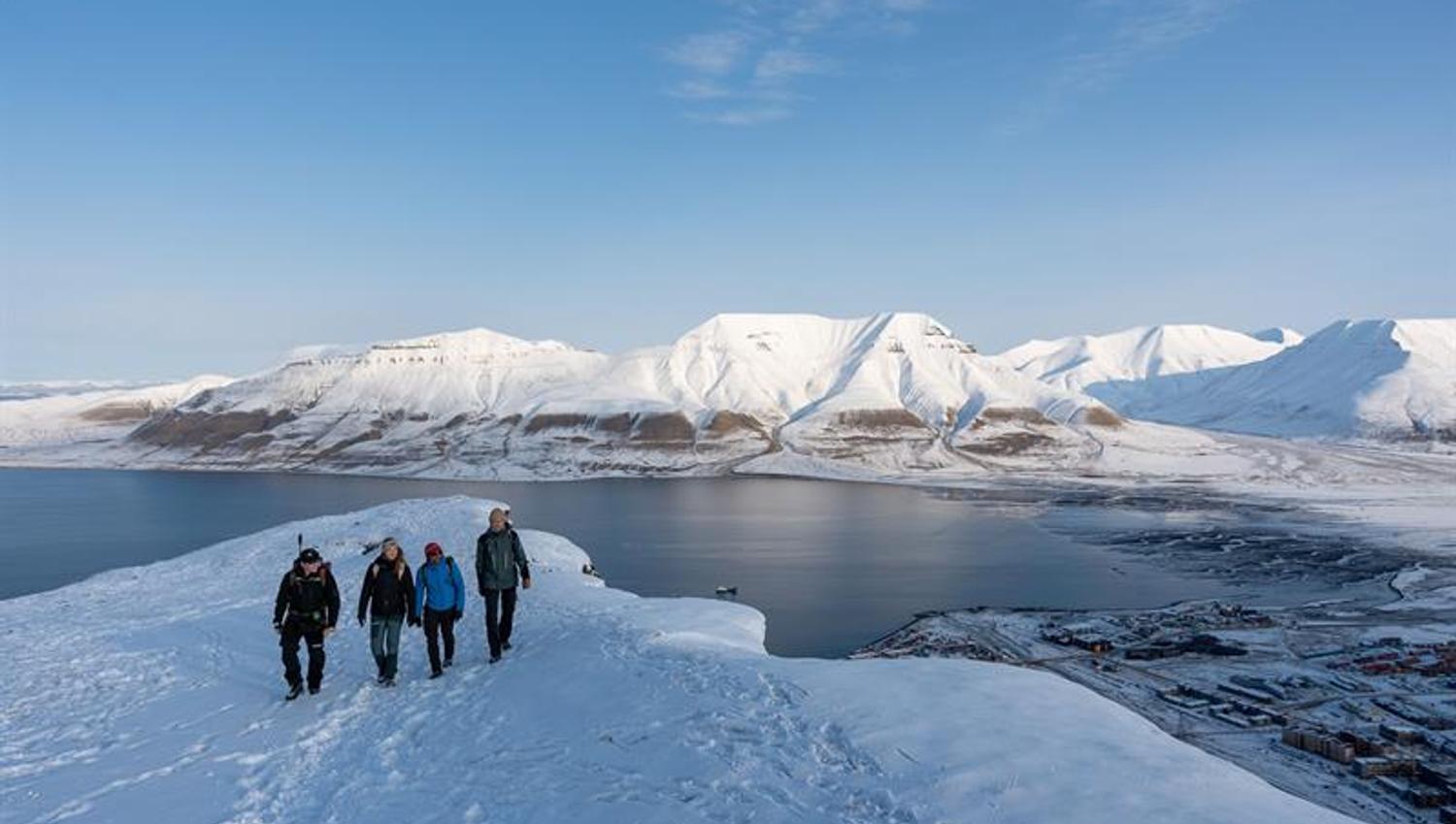 several people hiking on top of the snowcovered mountain
