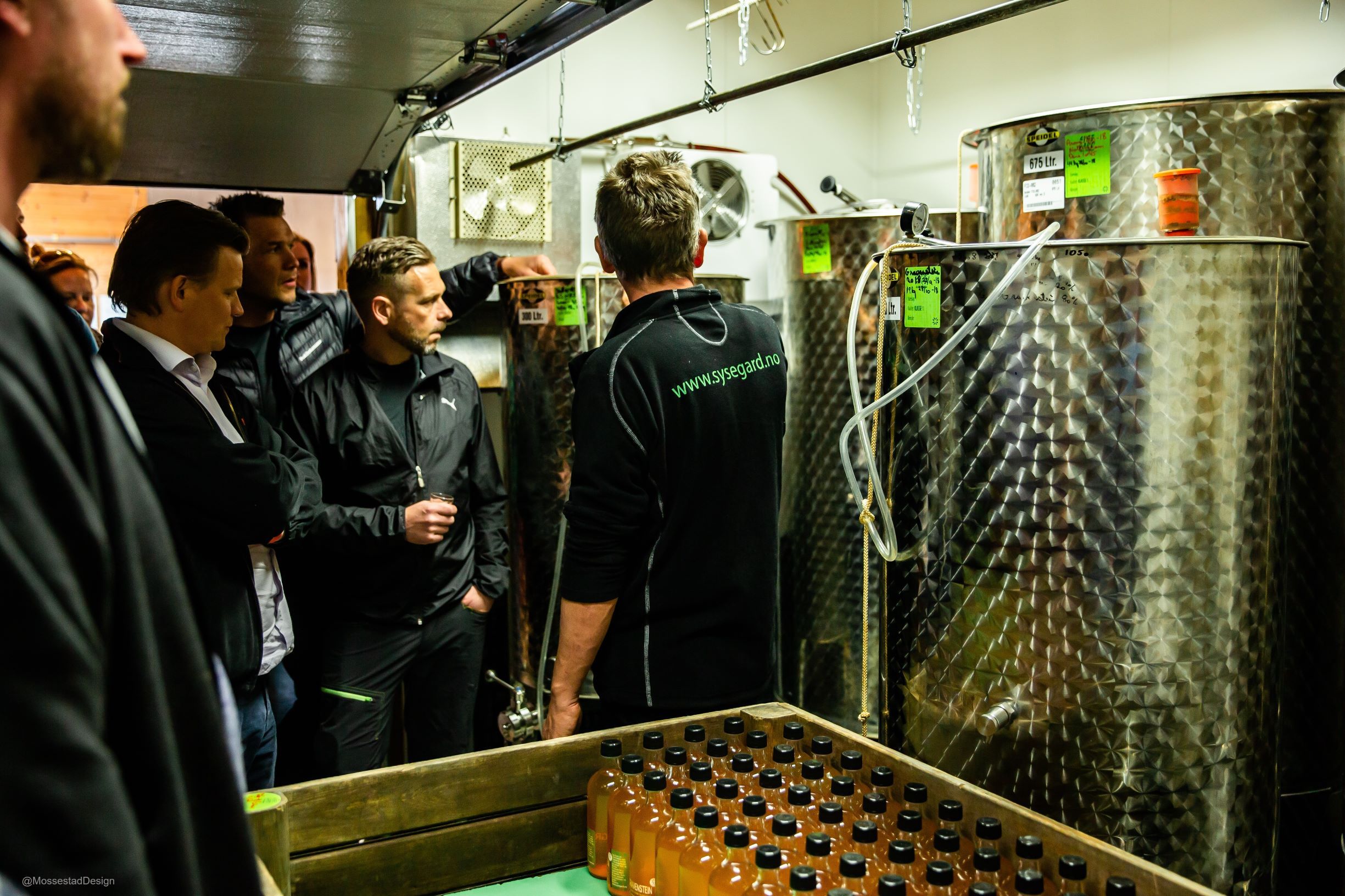Gruppe med besøkande får ei omsyning i siderproduksjon hos ein lokal produsent i Ulvik.