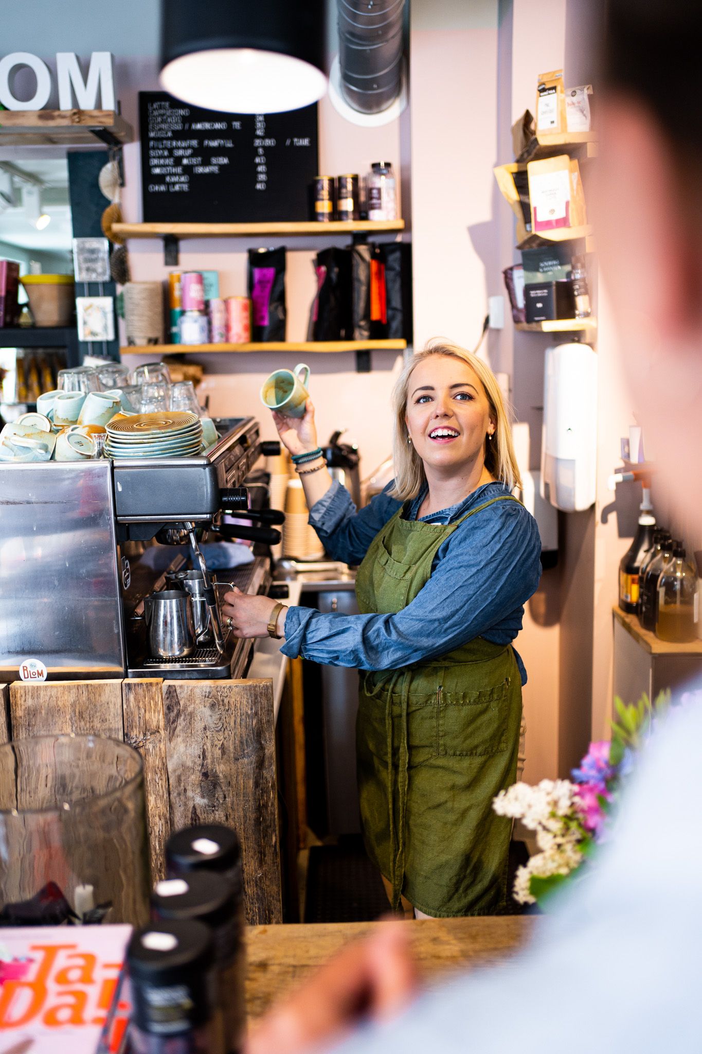 kvinne som lager kaffe mens hun snakker med en kunde