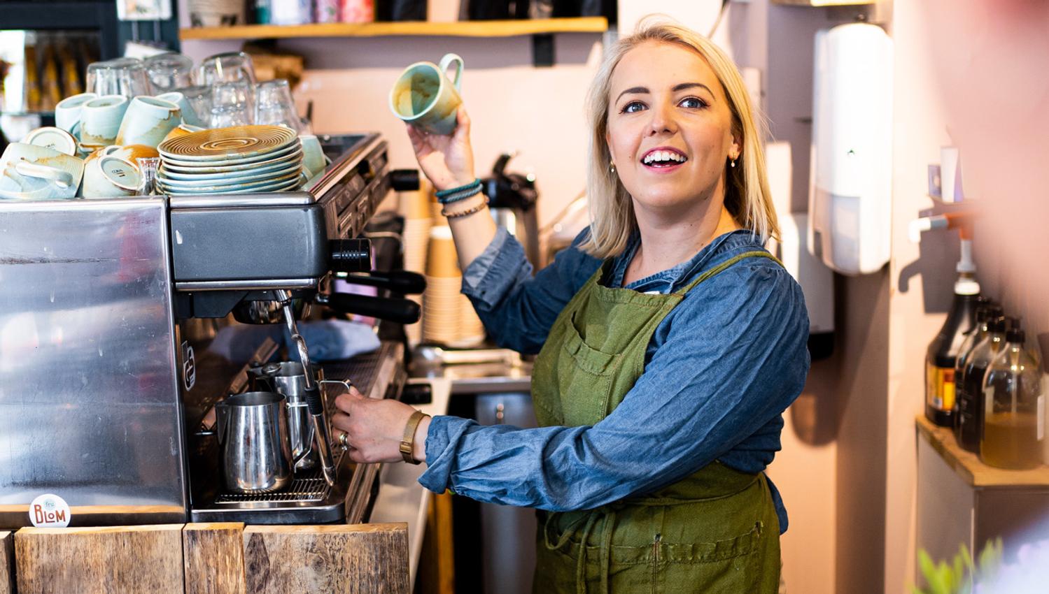 kvinne som lager kaffe mens hun snakker med en kunde