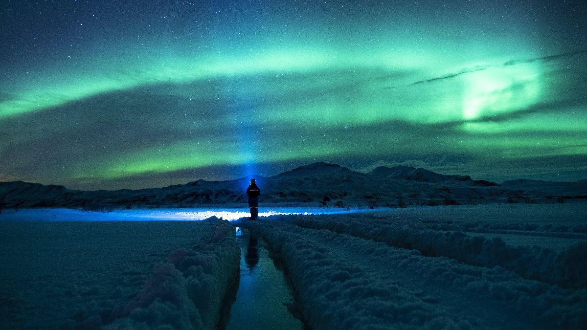 Person with headlamp under the northern lights