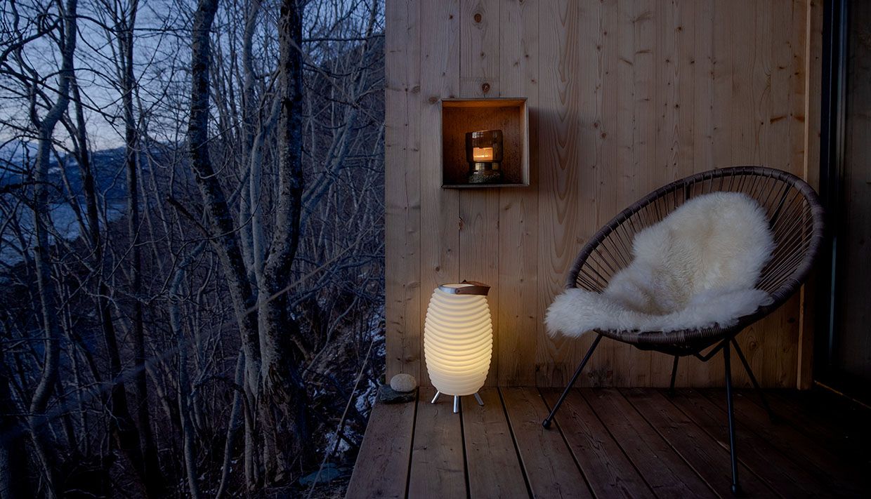 Cozy balcony with a sheepskin chair and lamp, surrounded by forest near Hardangerfjord.