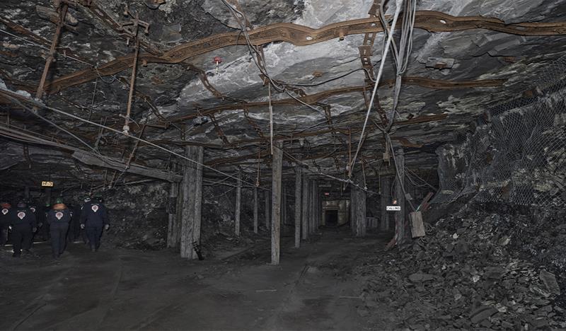 A group of guests with head lamps and helmets on, walking through a mine passage on a guided tour