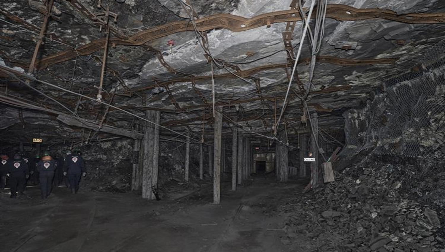 A group of guests with head lamps and helmets on, walking through a mine passage on a guided tour