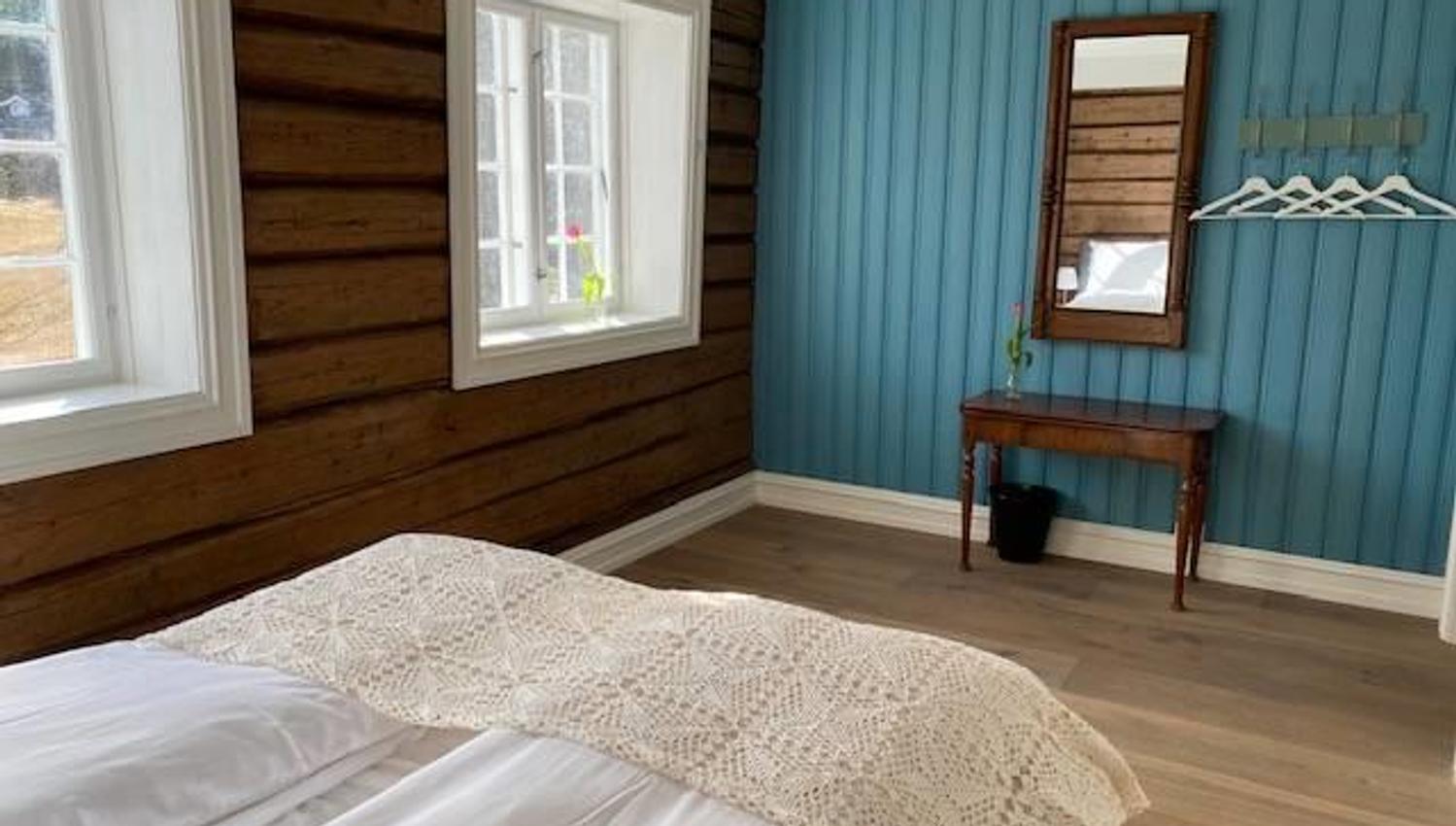 Blue room with double bed, a small table with mirror