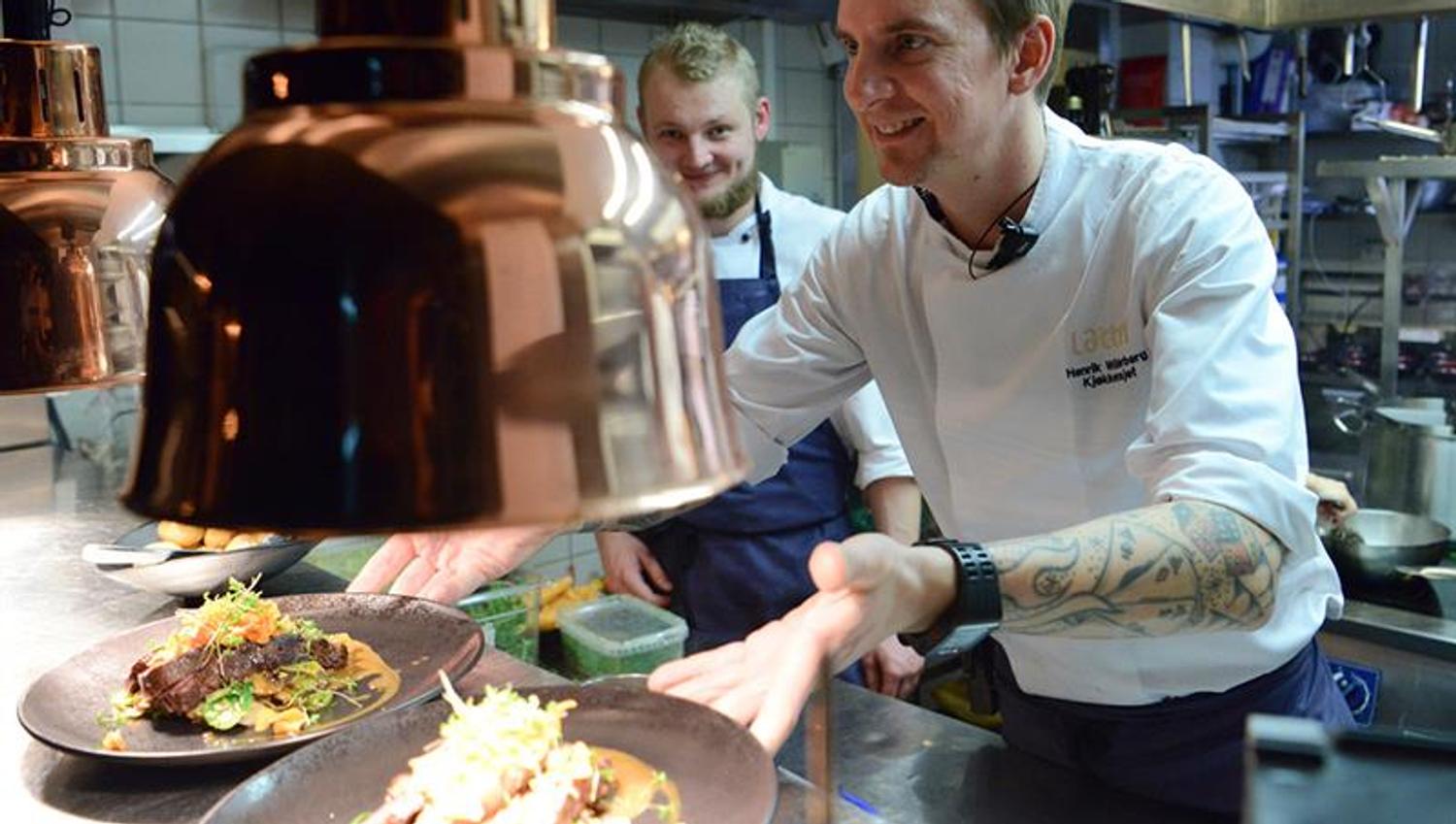 Two chefs laying dishes ready for serving.
