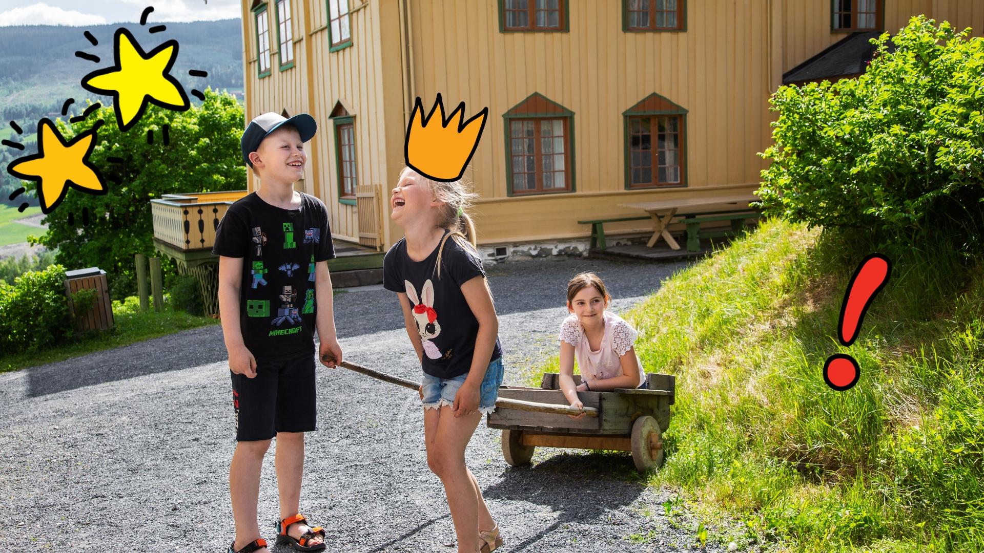 En gutt og en jente som trekker en jente i en gammeldags vogn.