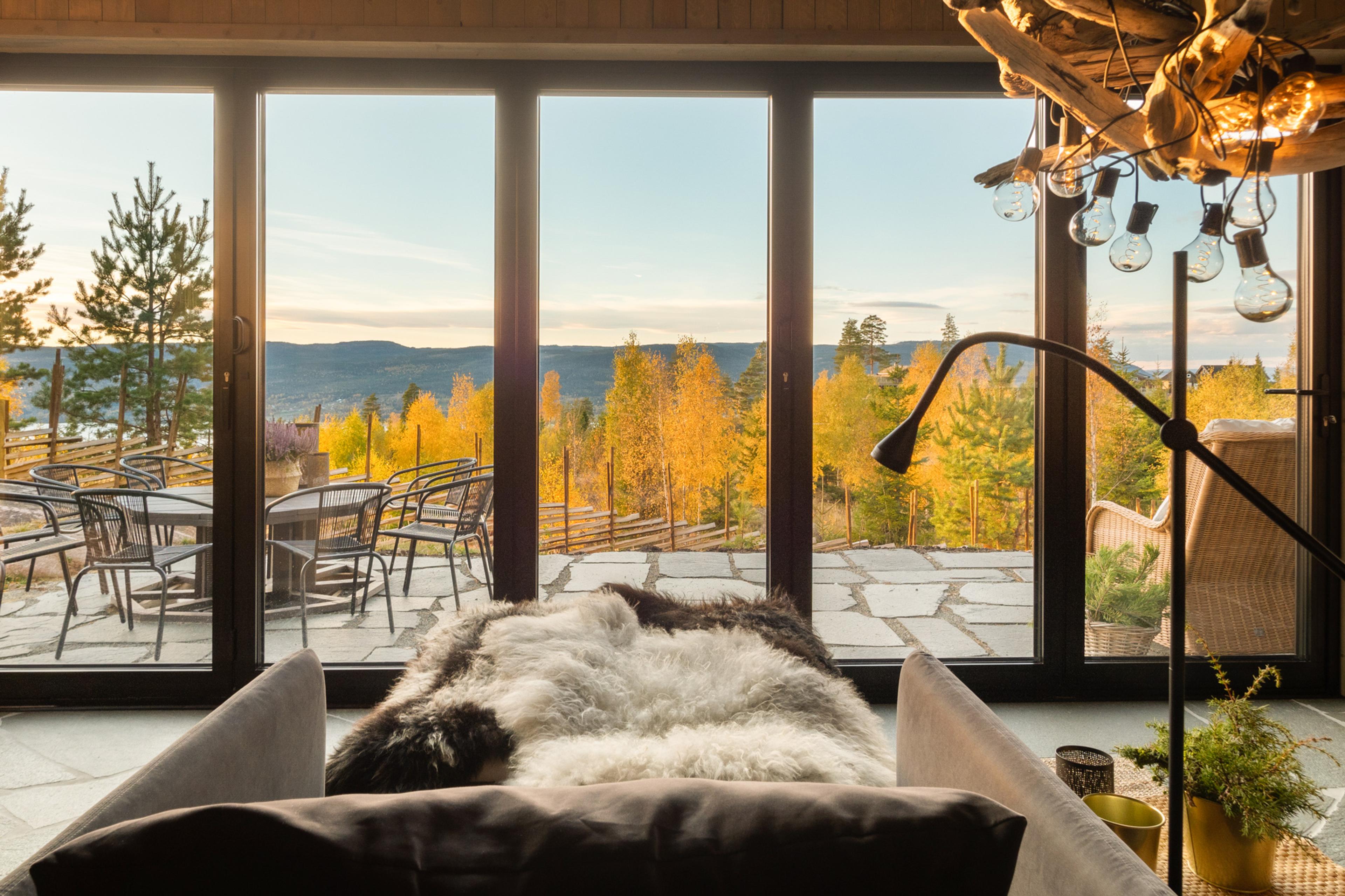 Utsikt fra ei hytte med en solnedgang med en sofa med skinnfell