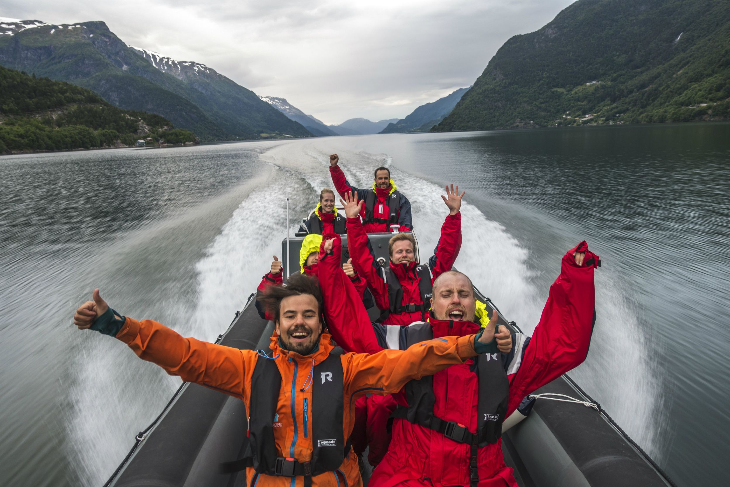 Smiling tourists enjoy a thrilling RIB safari on the Hardangerfjord.