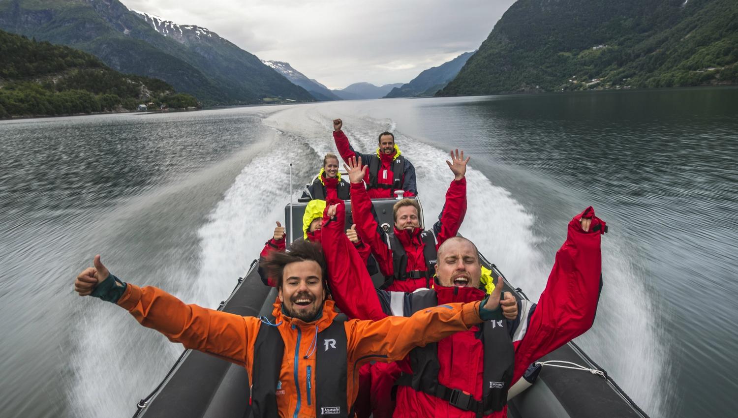 Smiling tourists enjoy a thrilling RIB safari on the Hardangerfjord.