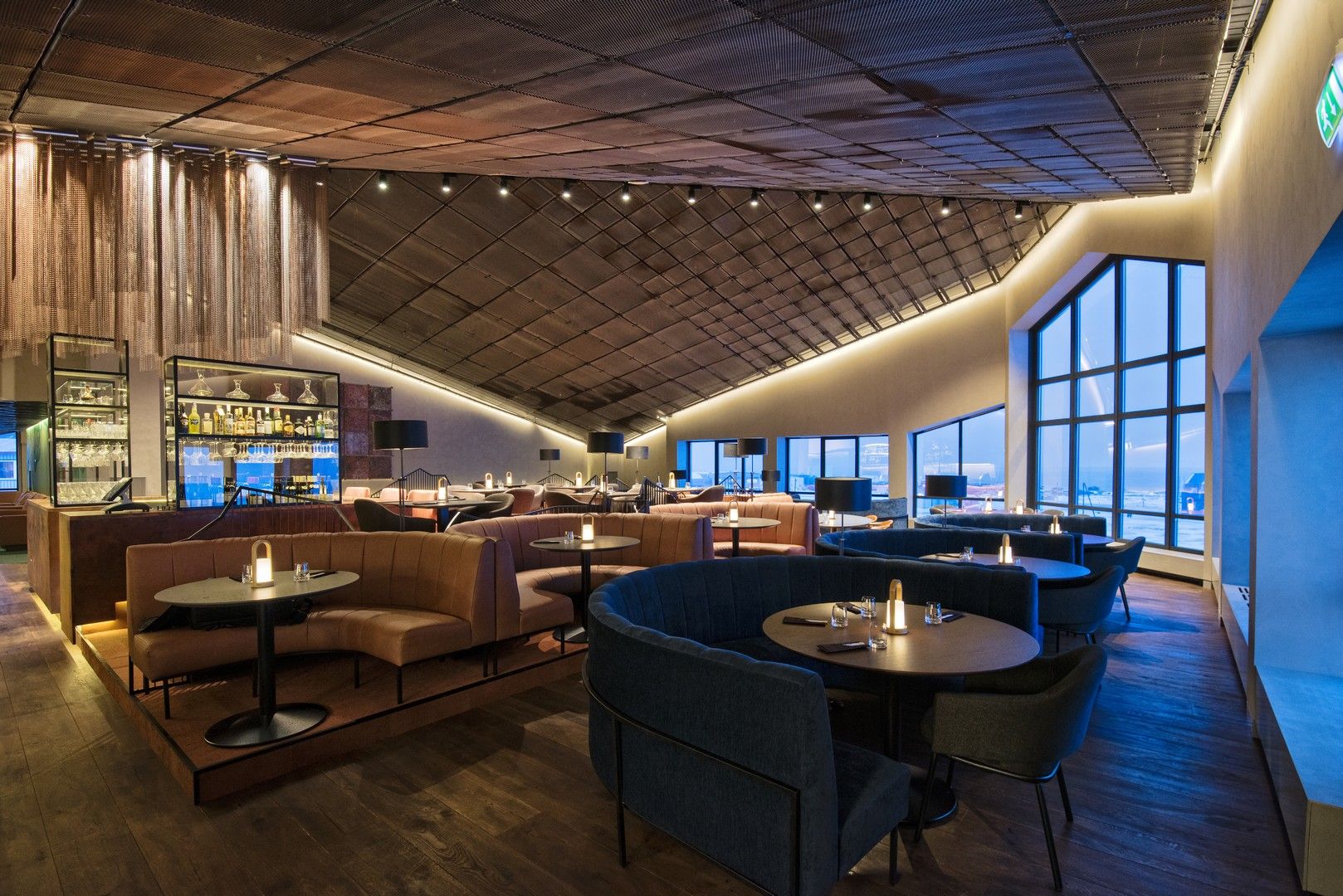 A restaurant with large windows letting in blue light from outside in the background