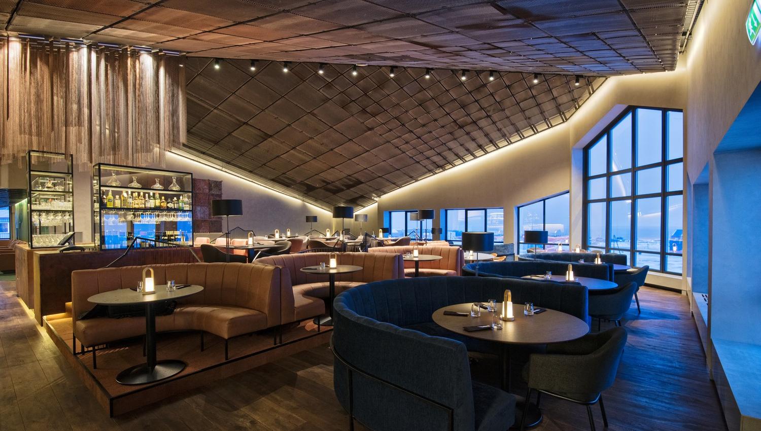 A restaurant with large windows letting in blue light from outside in the background