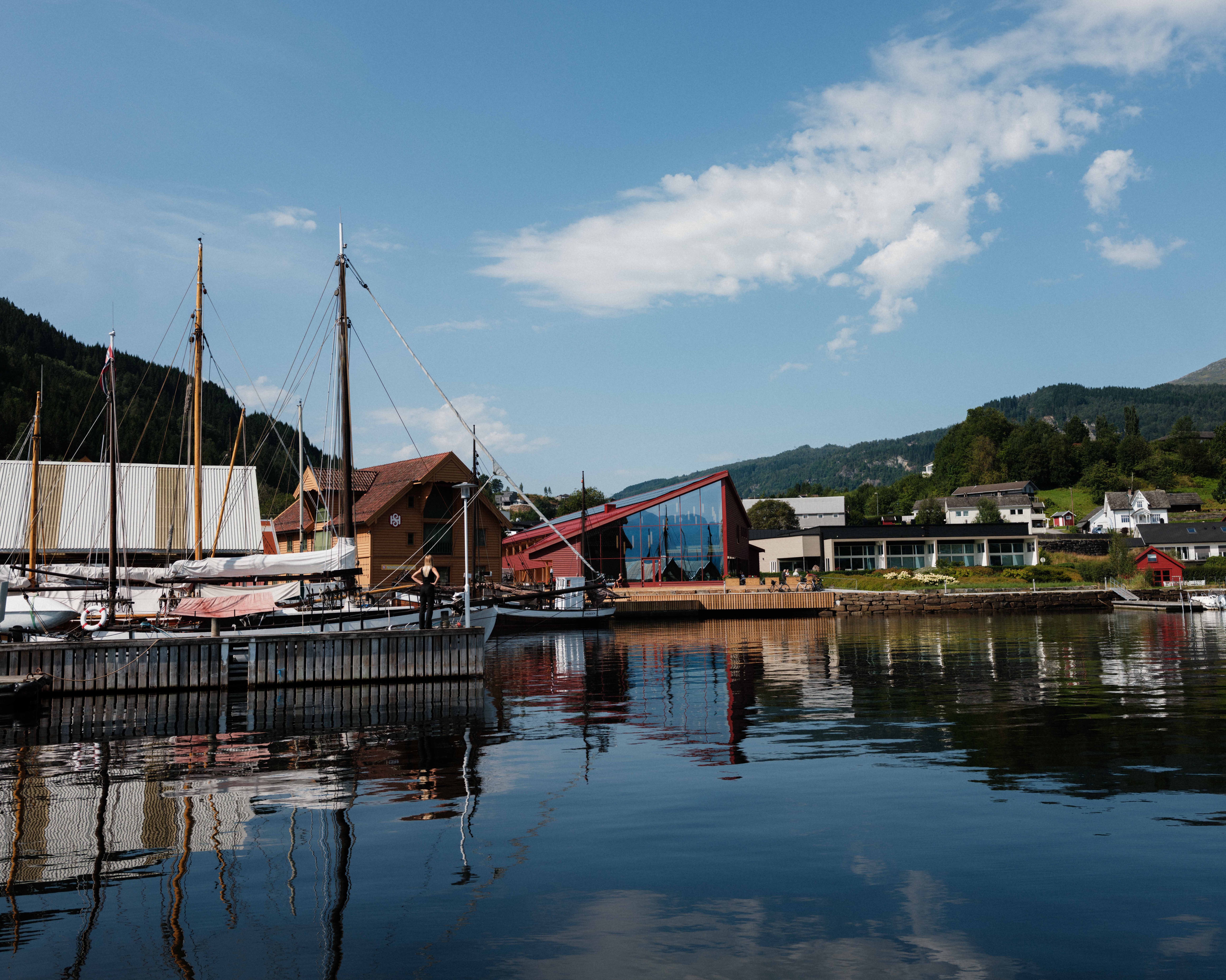 The Hardanger Maritime Centre seen from the water, with traditional vessels and the modern exhibition building.