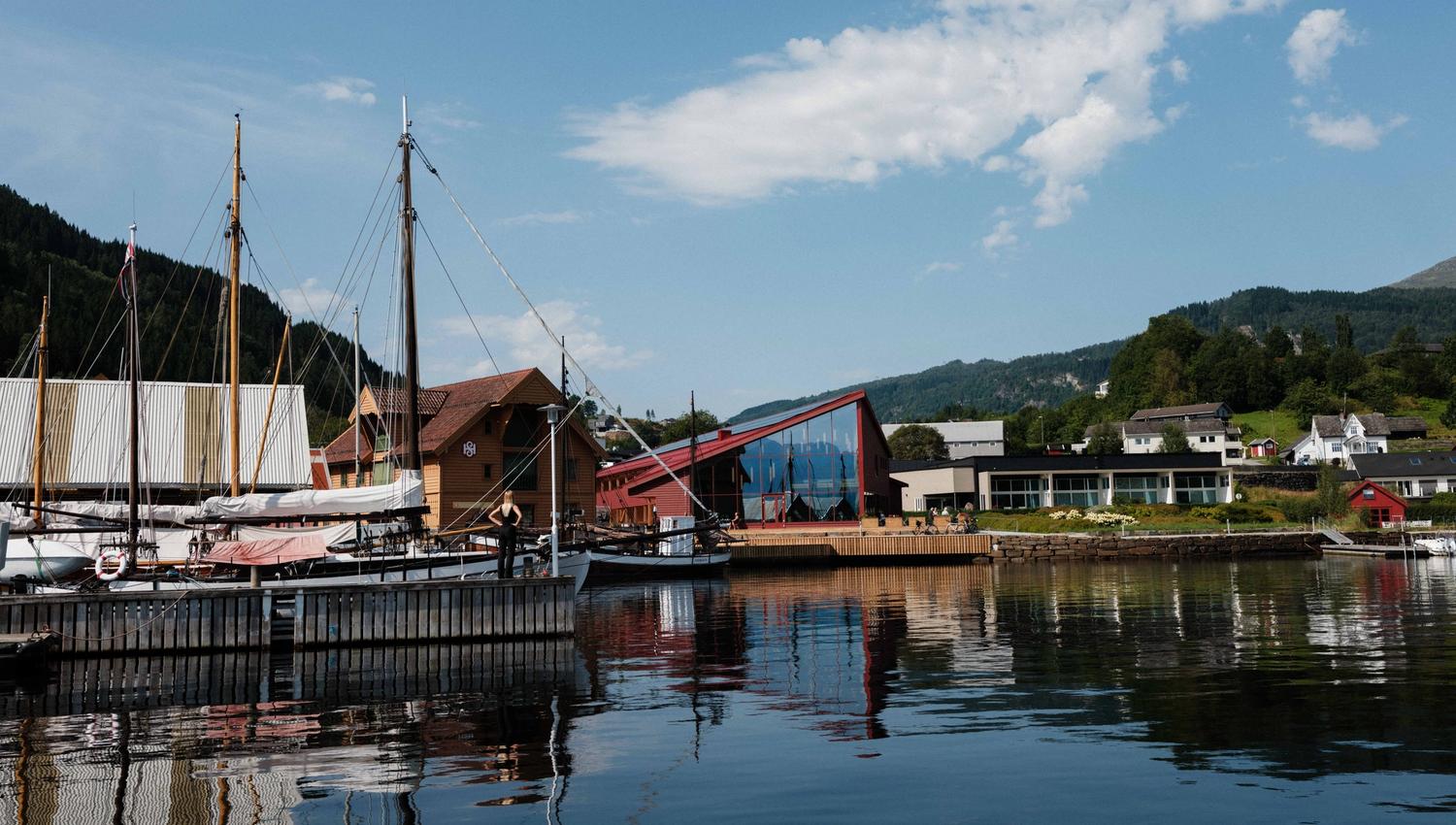 The Hardanger Maritime Centre seen from the water, with traditional vessels and the modern exhibition building.