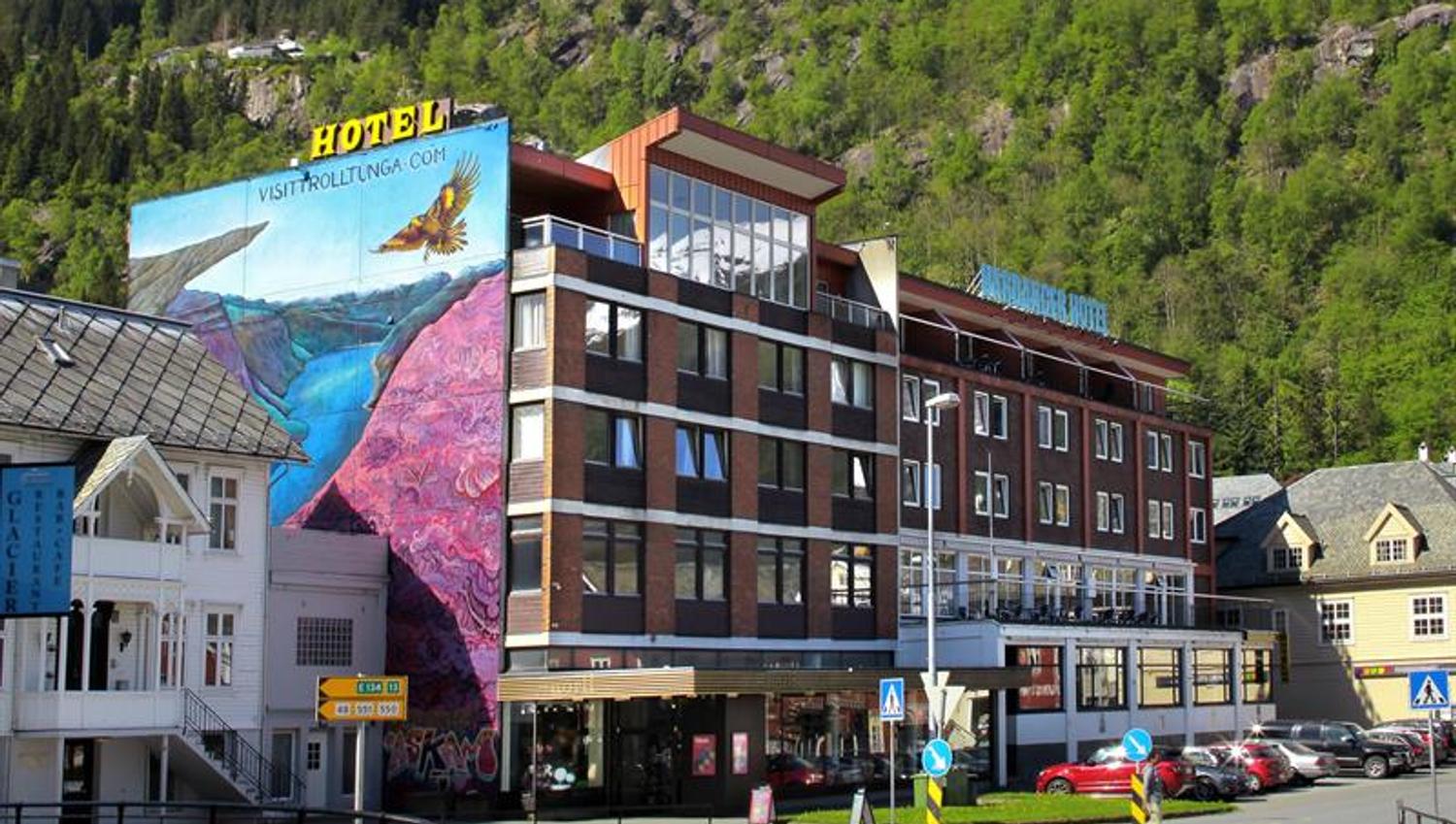 Hardanger Hotel i Odda med fargerik veggmåling og fjell i bakgrunnen.