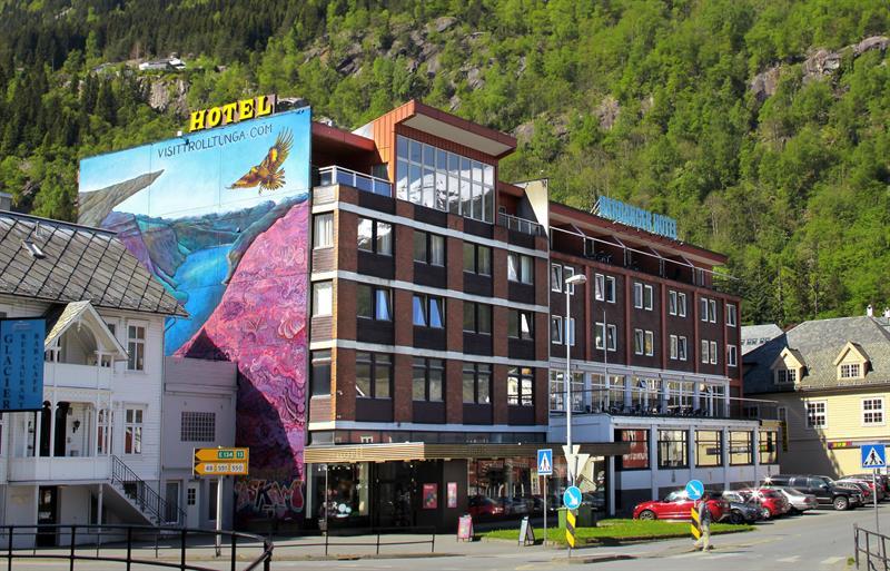 Hardanger Hotel i Odda med fargerik veggmåling og fjell i bakgrunnen.