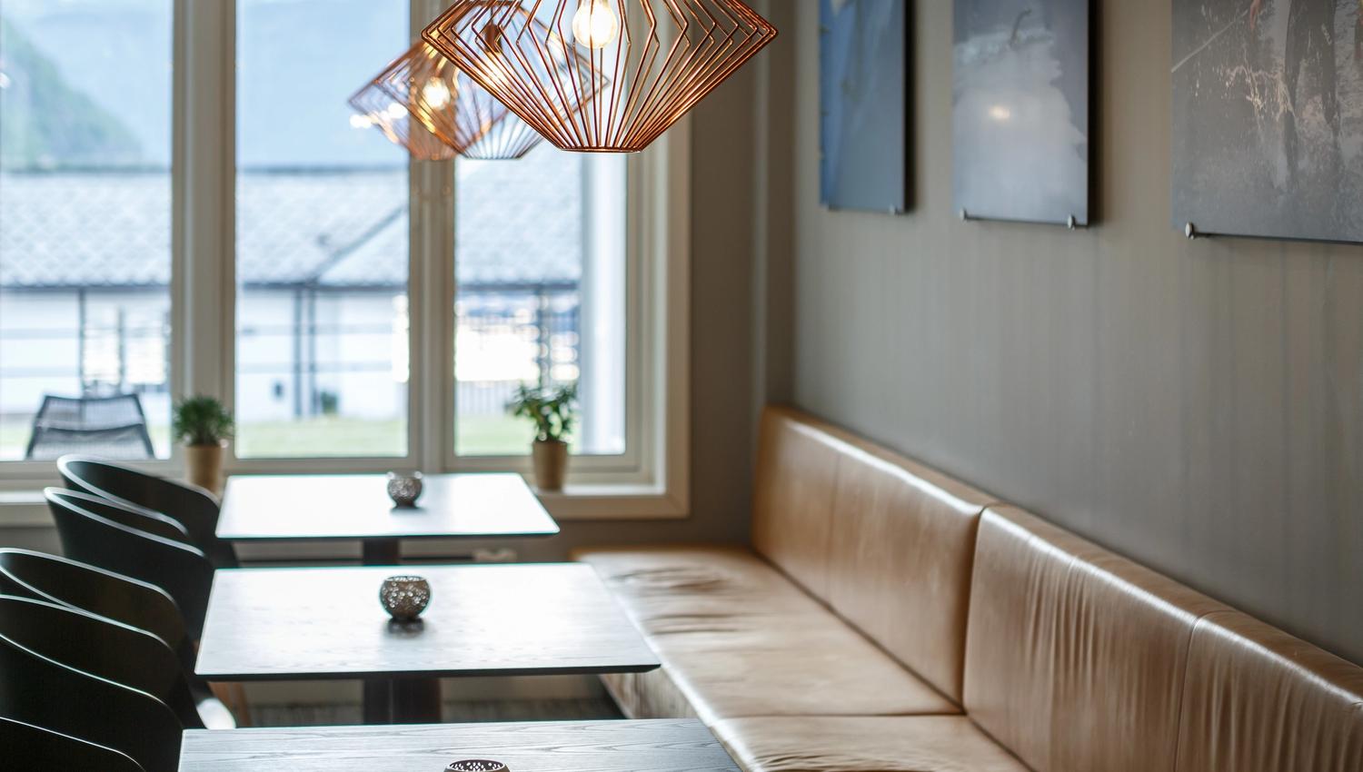 Stoler og bord i barområdet, med utsikt mot havna.