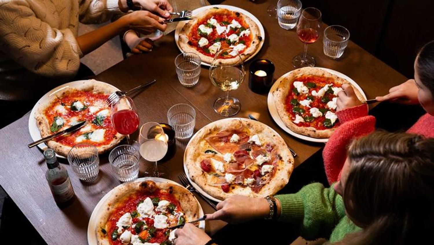 Fire personer som spiser pizza