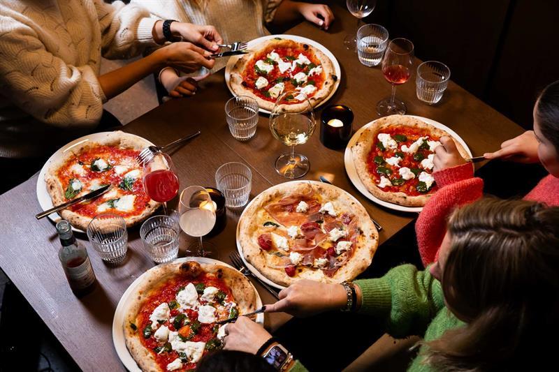 Fire personer som spiser pizza