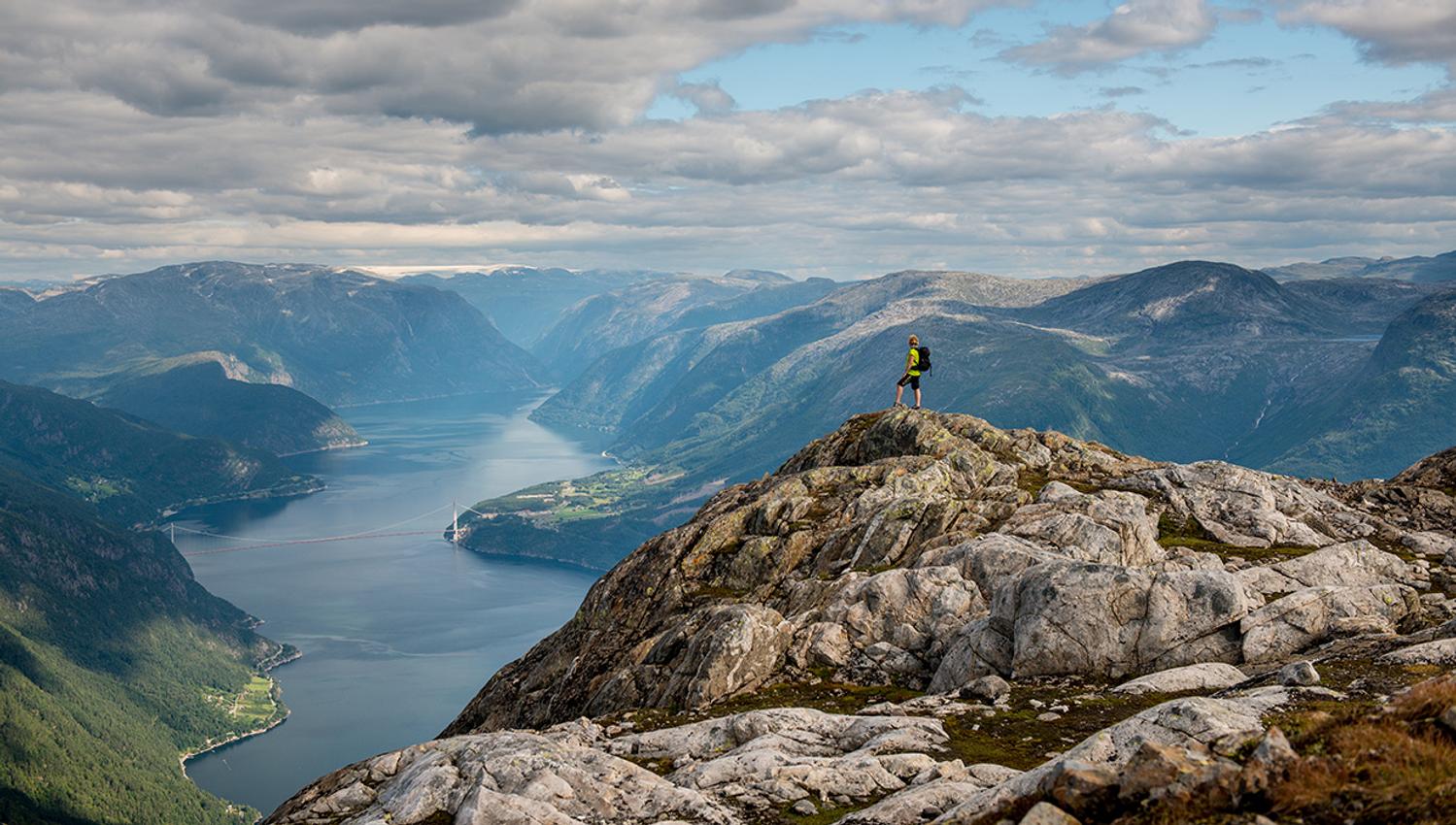 Ein einsam turgåar på fjelltoppen, ser utover den majestetiske Hardangerfjorden.