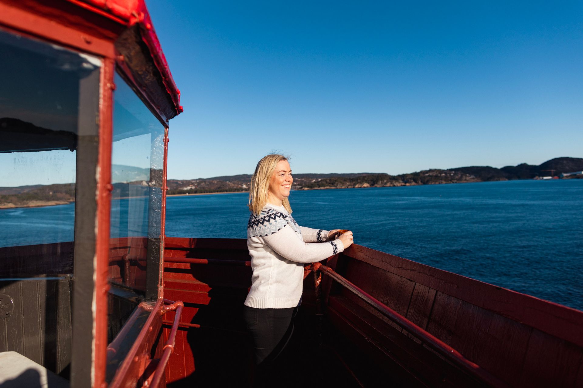 Dame som står oppe i fyret på Hatholmen og ser ut over havet