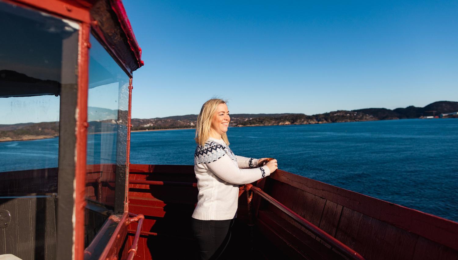 Dame som står oppe i fyret på Hatholmen og ser ut over havet