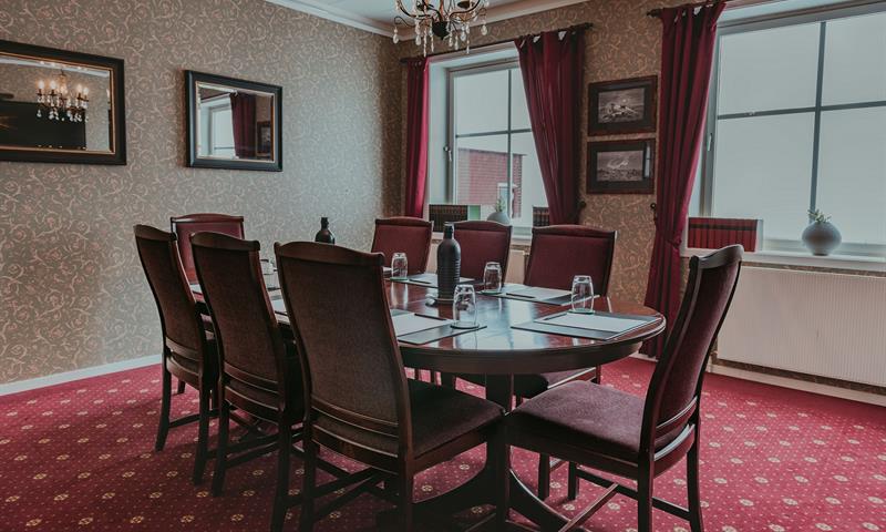 Et møterom med rødt gulv og stoler rundt et bord