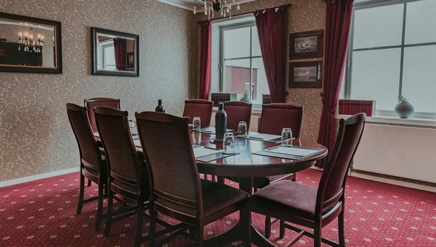 Et møterom med rødt gulv og stoler rundt et bord