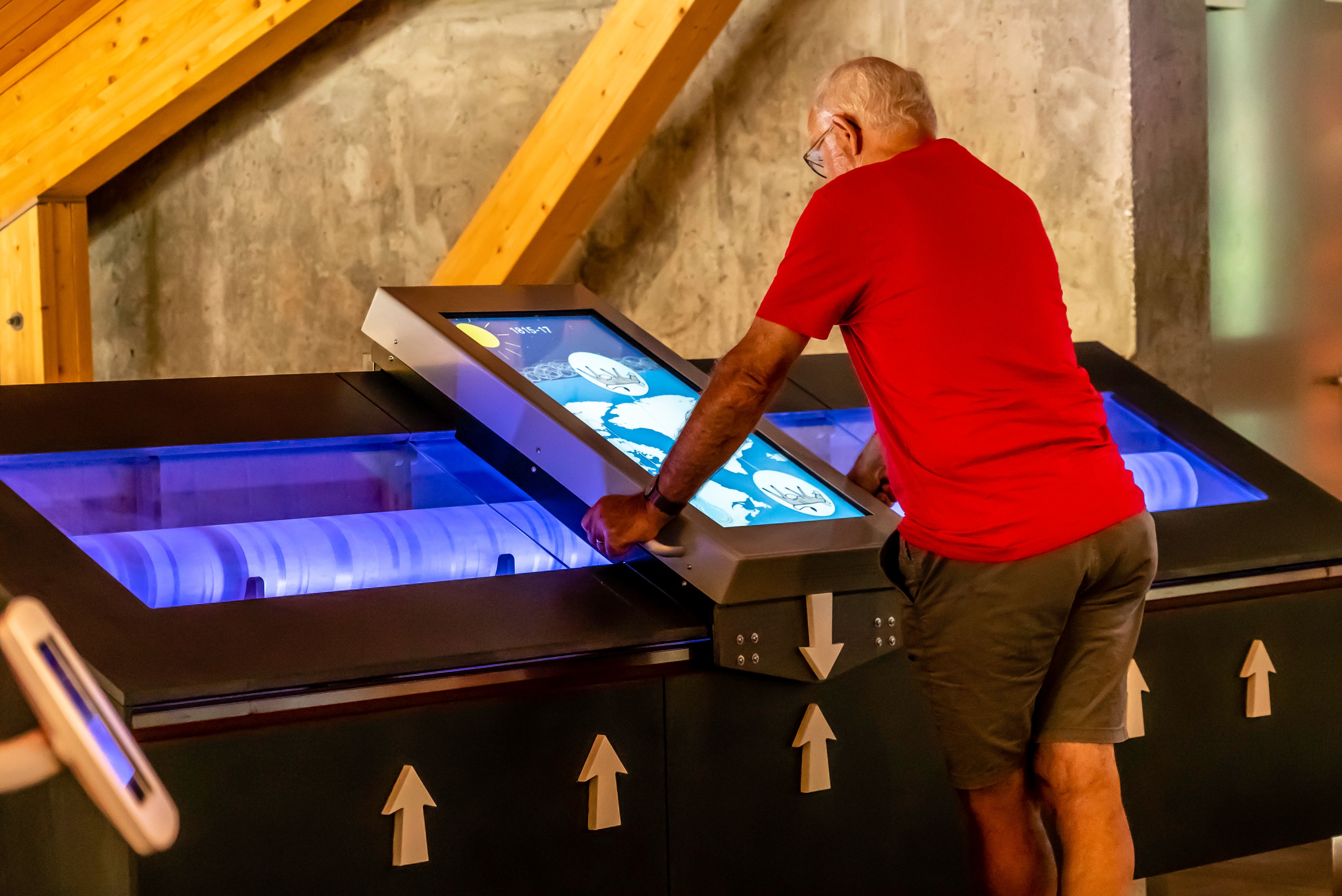 An older man is playing with an interactive exhibition piece.